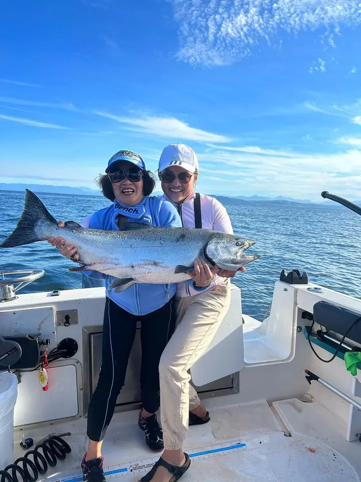 two women holding up a giant salmon they caught with Cliff's Chinook Charters