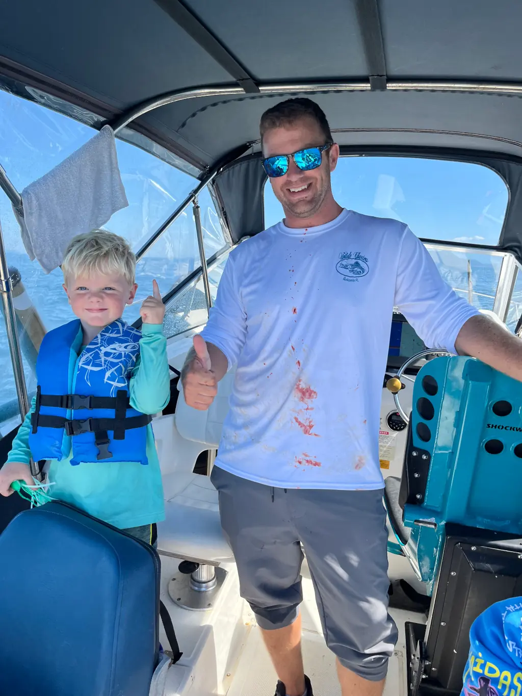 father and son giving a thumbs up on a fishing charter boat