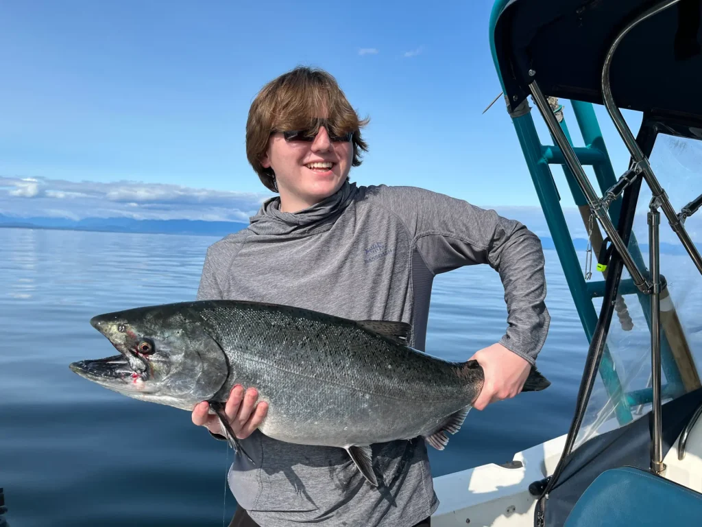 young man showing off a large salmon caught off Hornby Island