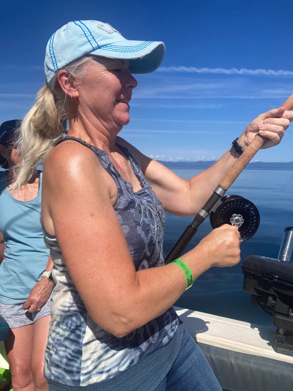 woman reeling in a fish on a charter off Comox