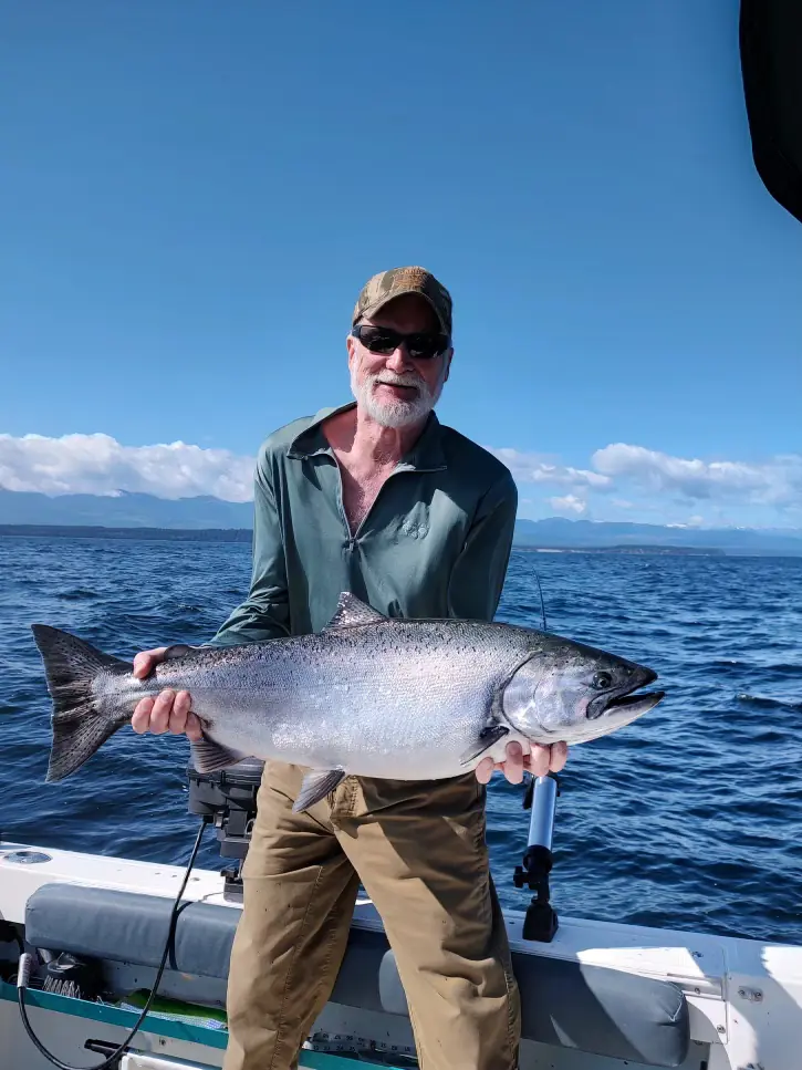 man holding up a large salmon caught near Hornby Island
