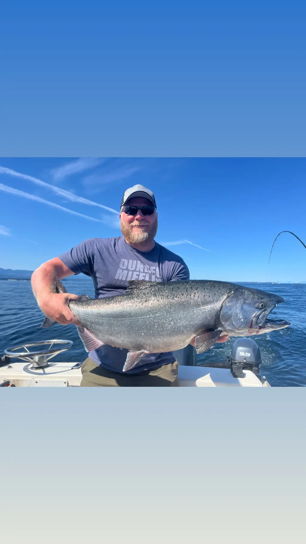 man displaying a large salmon from a fishing trip off Comox